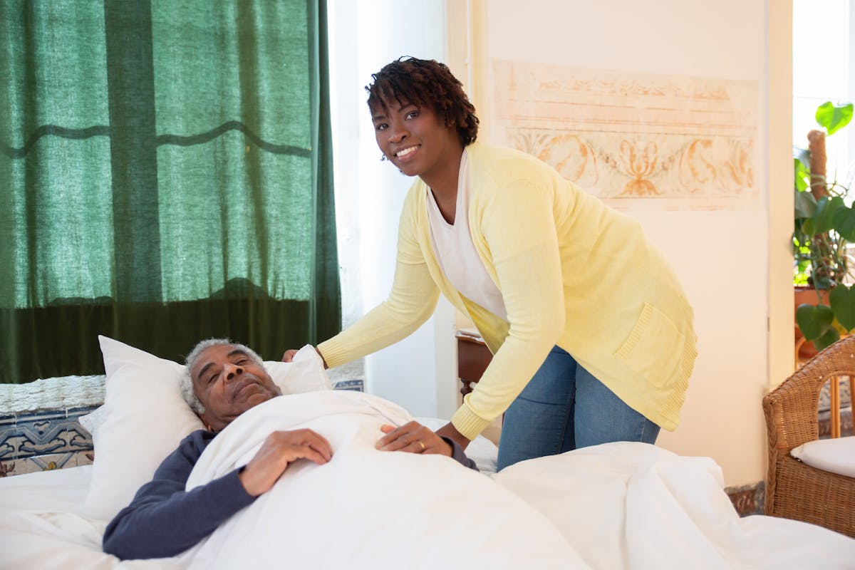 Caregiver helping an older adult rest in bed